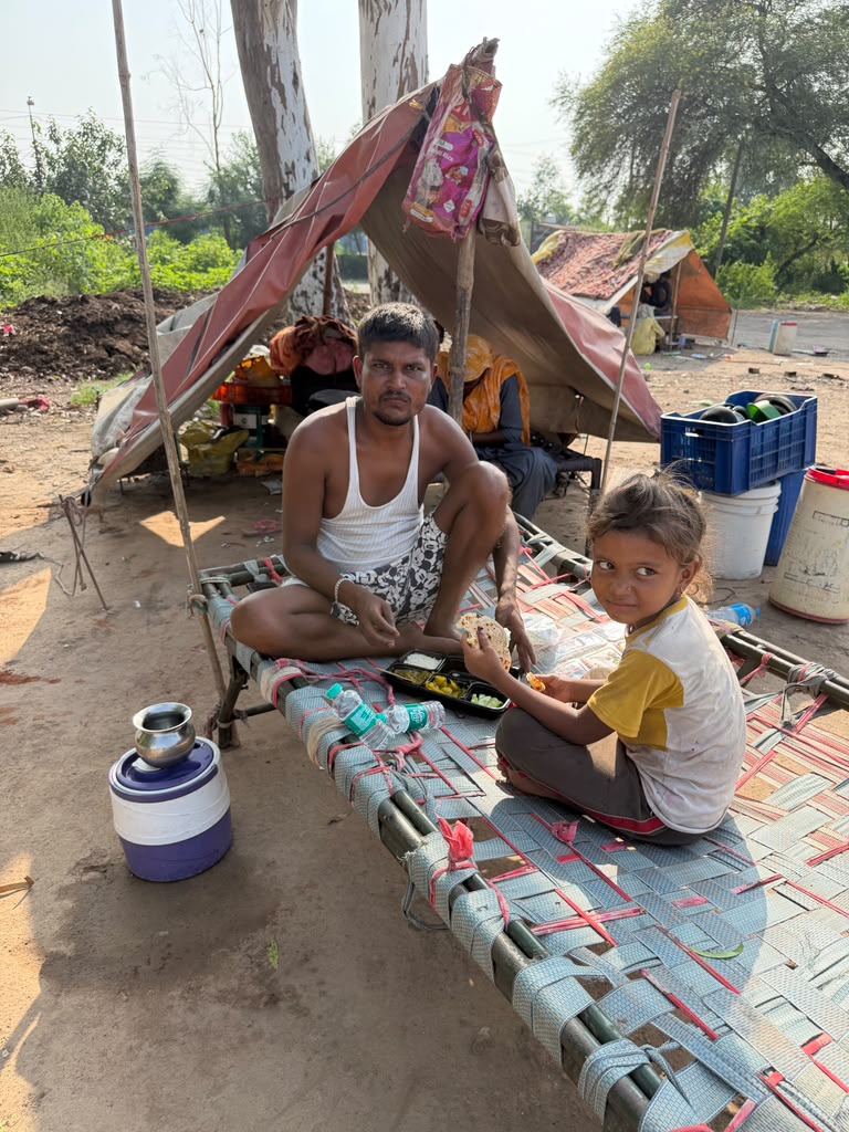 Underprivileged family having meals together by their shelter