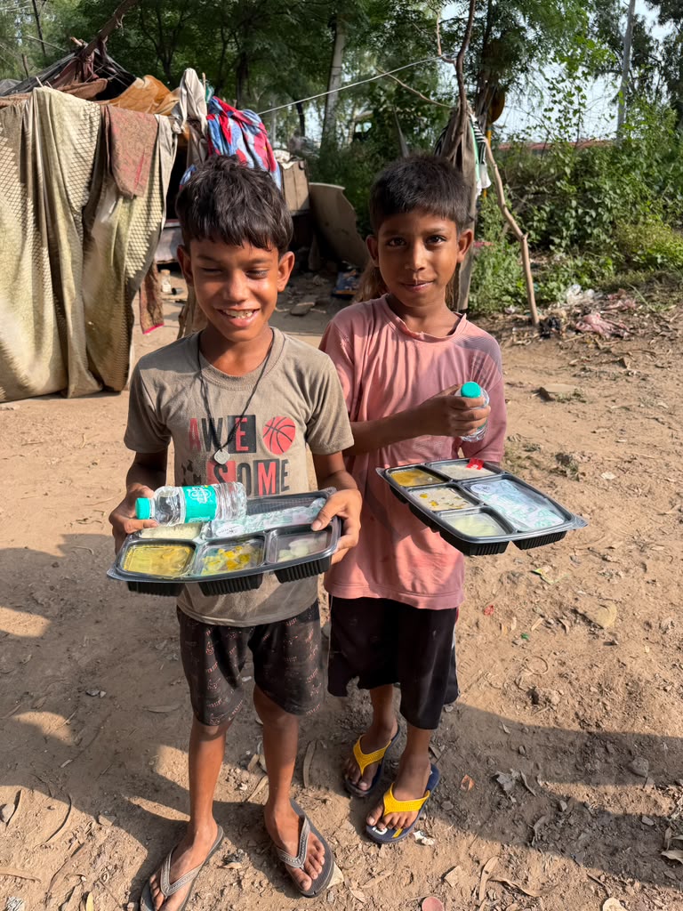 Two young boys smiling with their distributed lunch boxes